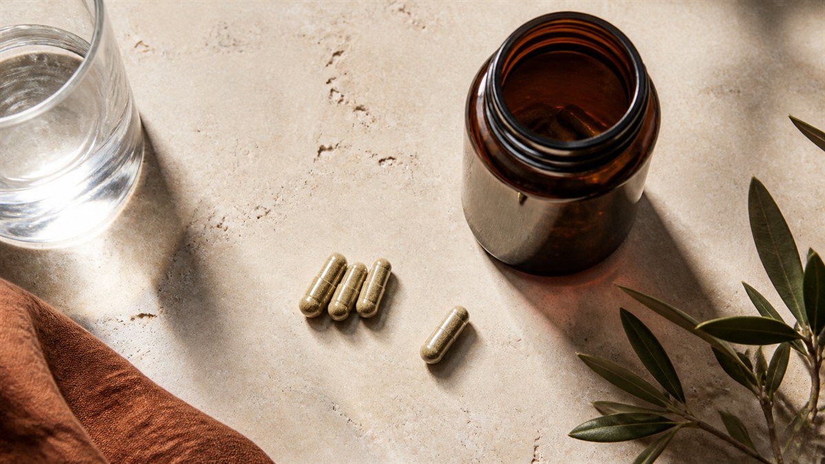 Three capsules grouped beside a single capsule and an open bottle.